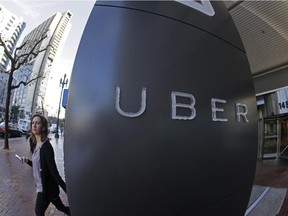 In this Tuesday, Dec. 16, 2014 photo, a woman leaves the headquarters of Uber in San Francisco. Uber X is priced lower than traditional taxi fares. As such, the taxi industry in Montreal has objected to it, saying drivers do not pay taxi licence fees, so they have an unfair advantage.