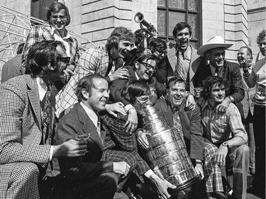 Montreal Canadiens Serge Savard and coach Scotty Bowman hold the Stanley Cup in 1973 surrounded by Jacques Laperriere, left, Ken Dryden, rear left, Guy Lafleur, 2nd from left rear, trainer Eddy Palchak next to Lafleur with arms around Savard and Bowman, Henri Richard, with cowboy hat, and goalie Michel Plasse to the right of Bowman.  (City of Montreal Archives)