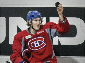 Canadiens forward Dale Weise holds up a puck that was fired into the bench during practice at the Bell Sports Complex in Brossard on Feb. 5, 2015.