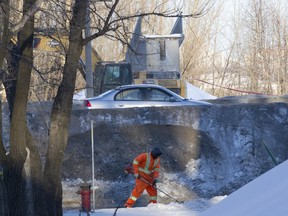 Crews clean up Bord de l'eau St. in the area around a demolished footbridge in Longueuil, south of Montreal, Wednesday February 11, 2015, after the bridge was torn down overnight. The bridge partially collapsed Tuesday night when it was struck by a dump truck, travelling westbound along Route 132.