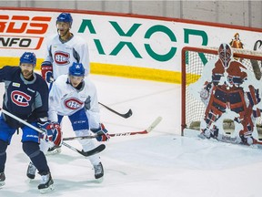 Canadiens players Andrei Markov, left, Alex Galchenyuk and Manny Malhotra take part in practice along with a plywood goalie filling in for Carey Price at the Bell Sports Complex in Brossard on Feb. 11, 2015.