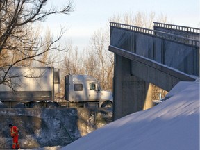 Traffic passes along highway 132 past the remains of a pedestrian overpass in Longueuil south of Montreal, Wednesday February 11, 2015. The overpass was partially demolished after part of it collapsed overnight, after it was hit by a dump truck.