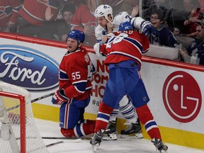 Nathan Beaulieu of the Montreal Canadiens jumps on David Clarkson of theToronto Maple Leafs after Clarkson had run Sergei Gonchar (left) of the Canadiens into the boards in NHL action during the first period at the Bell Centre in  Montreal on Saturday, February 14, 2015.