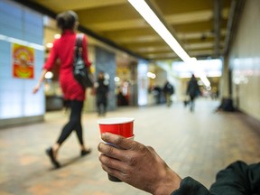 File photo: A homeless man panhandles at the Promenades Cathédrale near the McGill métro station in Montreal in February.