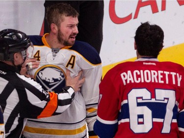 Buffalo Sabres defenceman Josh Gorges, left, is held back by the referee as he exchanges words with Montreal Canadiens left wing Max Pacioretty at the Bell Centre in Montreal on Tuesday, Feb. 3, 2015.