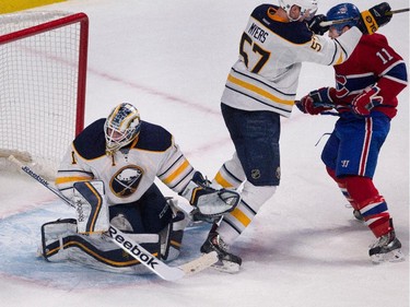 Montreal Canadiens right wing Brendan Gallagher, right, takes a stick to the head from Buffalo Sabres defenceman Tyler Myers as Buffalo Sabres goalie Jhonas Enroth, left, deflects the puck during NHL action at the Bell Centre in Montreal on Tuesday February 3, 2015.