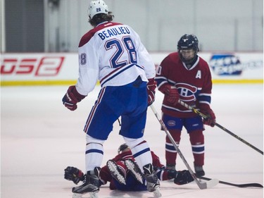 Nathan Beaulieu of the Montreal Canadiens knocks down Félix Trudeau of the AAA pee wee team called Conquérants des Basses-Laurentides, much to the delight of teammate William Lavigne, during a scrimmage at Bell Sports Complex in Brossard in Montreal, on Friday, February 6, 2015.