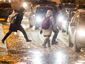 A woman jumps over flood waters on the corner of Metcalfe Street and Ste-Catherine Street during a flood caused by a broken a water main break near the McTavish reservoir in downtown Montreal on Monday, January 28, 2013.