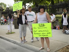 Duncan-Nawar, left, Magued Nawar and Therese Goudbout, right, protest against the suspension Dr. Gilles Mercier outside the Collège des Médecins du Québec in Montreal on Tuesday, July 24, 2012.