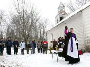 Aspergillum in hand, Archdeacon Edward Simonton sprinkles holy water towards the defiled cemetery at the historic St. John's Shrewsbury Anglican Church in the Gore township near Lachute north of Montreal Saturday, December 4, 2010.
