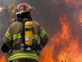 A fireman walks to a  fire.