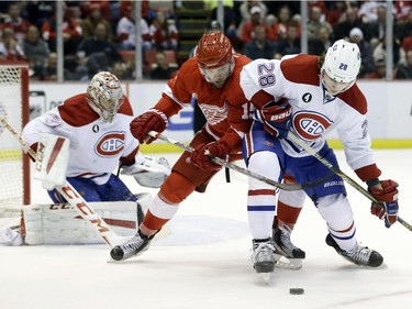 Detroit Red Wings centre Riley Sheahan and Montreal Canadiens defenceman Nathan Beaulieu (28) reach for the puck during the second period of an NHL hockey game Monday, Feb. 16, 2015, in Detroit.