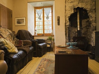 The living room is divided into two areas with one side having a comfortable nook with leather sofas and a wood stove placed where there once was a fireplace.