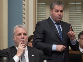 Quebec Education Minister Yves Bolduc speaks at the  legislature in Quebec City Feb. 25, 2015. Premier Philippe Couillard is at the left.