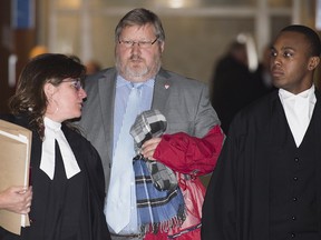 St-Clair Armitage, centre, leaves the Montreal Courthouse, Monday, March 16, 2015, where he appeared for a preliminary hearing in the MUHC fraud case.
