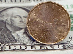 A Canadian dollar, or loonie, sits on top of its American counterpart in Toronto on Sept. 20, 2007. THE CANADIAN PRESS/Adrian Wyld ORG XMIT: CPW1804