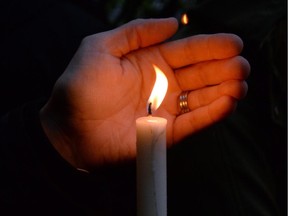A person hold a candle as people take part in a candlelight vigil outside RCMP headquarters in Moncton, N.B., on Friday, June 6, 2014. RCMP say a man suspected in the shooting deaths of three Mounties and the wounding of two others in Moncton was unarmed at the time of his arrest early Friday and was taken into custody without incident.