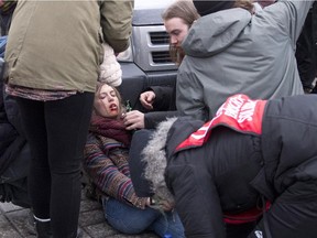 Naomi Tremblay-Trudeau is helped by demonstrators after tear gas was shot in her face during an anti-austerity protest, Thursday, March 26, 2015 in front of the legislature in Quebec City.