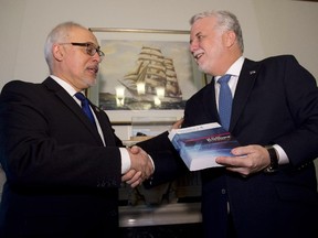 Quebec Finance Minister Carlos Leitao, left, gives a copy of the budget speech to Quebec Premier Philippe Couillard Thursday, March 26, 2015 at the premier's office in Quebec City.