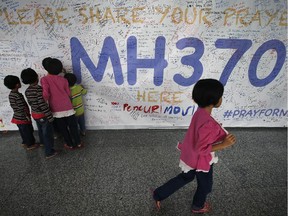 Children read messages and well wishes displayed for all involved with the missing Malaysia Airlines jetliner MH370 on the walls of the Kuala Lumpur International Airport, Thursday, March 13, 2014 in Sepang, Malaysia.