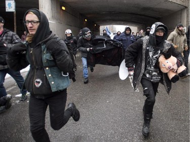 Demonstrators run away from riot police moving in during the annual anti-police brutality demo, Sunday, March 15, 2015 in Montreal.