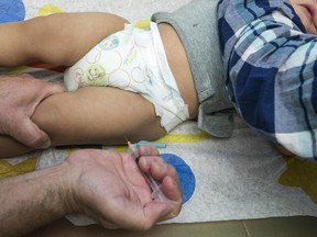 FILE - In this Jan. 29, 2015 file photo, a pediatrician uses a syringe to vaccinate a 1-year-old with the measles-mumps-rubella (MMR) vaccine in Northridge, Calif.