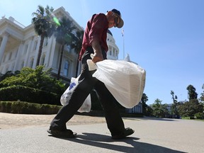 In this file photo taken Tuesday, Aug. 12, 2014, plastic single-use bags are carried past the State Capitol in Sacramento, Calif. Gov. Jerry Brown signed legislation last September imposing the first U.S. statewide ban on single-use plastic bags. Will Montreal now follow suit?