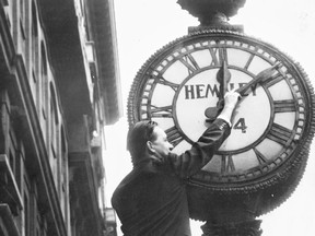 A man moves Hemsley's clock on St-Jacques St. ahead an hour for daylight saving time, on April 29, 1950.