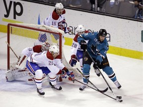 San Jose Sharks' Joe Thornton, right, tries to skate around Montreal Canadiens' Manny Malhotra (20) and Nathan Beaulieu (28)  during the first period of an NHL hockey game Monday, March 2, 2015, in San Jose, Calif.