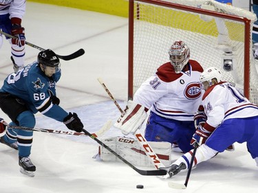 Montreal Canadiens goalie Carey Price, centre, and centre Tomas Plekanec, right, defend a shot by San Jose Sharks' Melker Karlsson (68) during the first period of an NHL hockey game Monday, March 2, 2015, in San Jose, Calif.