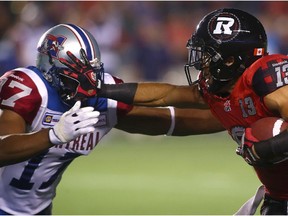 OTTAWA, ON - SEPTEMBER 26: Khalil Paden #13 of the Ottawa Redblacks straight-arms Billy Parker #17 of the Montreal Alouettes as he rushes with the ball during a CFL game at TD Place Stadium on September 26, 2014 in Ottawa, Ontario, Canada.