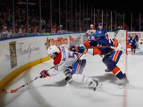 David Desharnais #51 of the Montreal Canadiens is checked by Brian Strait #37 of the New York Islanders during the third period at the Nassau Veterans Memorial Coliseum on March 14, 2015 in Uniondale, New York. The Canadiens defeated the Isalnders 3-1.