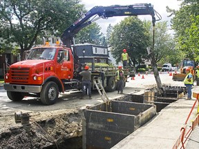A Montreal city work crew moves a section of old pipe from under Cavendish Blvd. to a truck on Thursday, July 8, 2009.