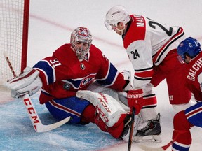 Montreal Canadiens goalie Carey Price makes a save against Carolina Hurricanes centre Brad Malone as Montreal Canadiens right wing Brendan Gallagher tries to clear him from the goal crease at the Bell Centre on Thursday, March 19, 2015.