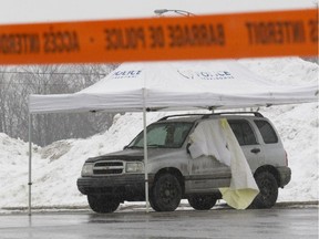 A car in which the body of a man in his 60s was found, sits enclosed in a police perimeter in a parking lot on Arthur Chapleau Blvd. in Bois-des-Filion, north of Montreal, Saturday March 21, 2015.  Police say there were marks of violence on body and they are treating it as a homicide.