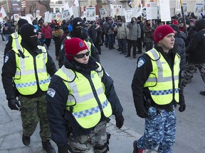 Montreal police officers walk next to Montreal white-collar protesters in front of Montreal city hall on Monday, March 23, 2015.
