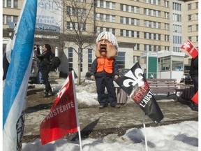 A protester wearing an effigy of Quebec Health Minister Géatan Barrette, joins striking Université de Montréal students, along with the union representing hospital workers for an anti-austerity demonstration in front of the Sainte Justine hospital on Wednesday.