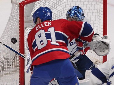 Tampa Bay Lightning goalie Ben Bishop looks at loose puck flying next to Montreal Canadiens' Lars Eller during first-period action in Montreal on Monday, March 30, 2015.