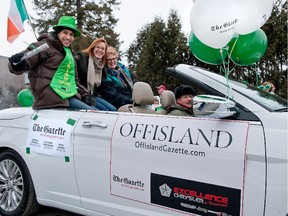 Reporter Jason Magder, editor Brenda O'Farrell and reporter Kathryn Greenway of The Montreal Gazette, wave to crowds lining Main Road during the St. Patrick's Day parade in Hudson on Saturday, March 16, 2013.