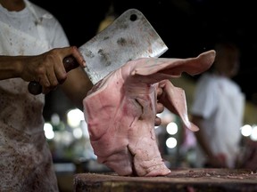 A butcher chops a head of a pig at a wet market in Manila on January 29, 2015.  The Philippines beat expectations after a surprising economic rebound saw growth accelerate in the last three months of 2014, with officials predicting further strong expansion in the year ahead.