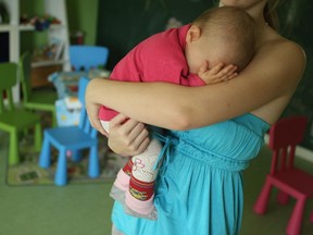 BERLIN, GERMANY - OCTOBER 05:  Single mother Nancy Kett, 19, cradles her 11-month-old daughter Lucy in the playroom of the "Jule" facility for single parents in Marzahn-Hellersdorf district on October 5, 2012 in Berlin, Germany. The Jule project helps single parents by helping them to find jobs, job training and housing, advice on child development and day care in Marzahn-Hellersdorf, a district in east Berlin with high levels of unemployment and social problems. Currently 14 single mothers and one single father are participaring at Jule, which opened its doors in the spring of 2012.