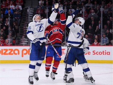 David Desharnais of the Montreal Canadiens jumps to grab the falling puck against Braydon Coburn, 55, and Victor Hedman, 77, of the Tampa Bay Lightning at the Bell Centre on Tuesday, March 10, 2015.