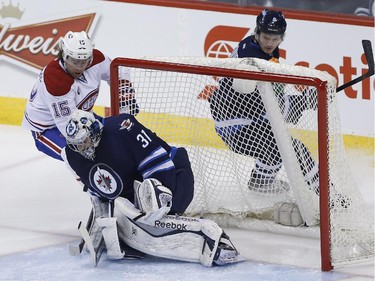 Winnipeg Jets goaltender Ondrej Pavelec (31) saves the shot by Montreal Canadiens' Pierre-Alexandre Parenteau (15) as Jets' Jacob Trouba (8) looks on during first period NHL action in Winnipeg on Thursday, March 26, 2015.