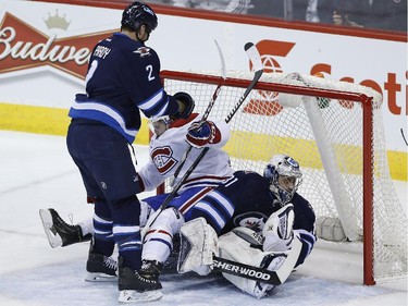 Montreal Canadiens' Alex Galchenyuk (27) gets pushed onto Winnipeg Jets goaltender Ondrej Pavelec (31) by Jets' Adam Pardy (2) after Pavelec made the save during first period NHL action in Winnipeg on Thursday, March 26, 2015.