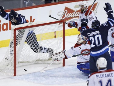 Winnipeg Jets' Jim Slater (19) and Lee Stempniak (20) celebrate a Dustin Byfuglien (33) shot that trickled through the legs of Montreal Canadiens goaltender Dustin Tokarski (35) for the goal as Habs' Greg Pateryn (64), Nathan Beaulieu (28) and Tomas Plekanec (14) look on during first period NHL action in Winnipeg on Thursday, March 26, 2015.