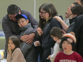 Joseph Gunner, left, uncle of police officer and fire victim Charlie Gunner, stands with other family members and friends of the five men who perished in a cabin fire in Mistissini, as they gather around photographs of the men at a memorial service in the Cree village north of Montreal, Friday April 3, 2015.