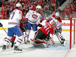 Senators goalie Craig Anderson reaches back with his stick to ensure the puck doesn't trickle in as Canadiens Andrei Markov (right), Max Pacioretty (left) and Devante Smith-Pelly crash the net during Game 3 action on April 19, 2015.