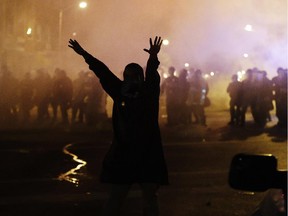 A protestor walks away as police in riot gear advance on the crowd after a 10 p.m. curfew went into effect in the wake of Monday's riots following the funeral for Freddie Gray, Tuesday, April 28, 2015, in Baltimore.