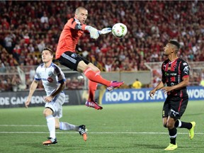 Armando Alonso, right, of Costa Rica's Alajuelense fights for control of the ball with Impact goalkeeper Evan Bush as defender Donny Toia races back into the play during the semifinal match of the CONCACAF Champions League in the Alejandro Morera Soto Stadium in Alajuela, Costa Rica, Tuesday, April 7, 2015.