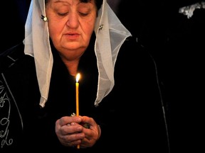 A woman holds a candle during a religious service at the cathedral in Etchmiadzin, outside Yerevan, on April 23, 2015, ahead of the canonization ceremony for the Martyrs of the Armenian Genocide. Armenians prepare to commemorate on April 24 a hundred years since 1.5 million of their kin were massacred by Ottoman forces, as a fierce dispute still rages with Turkey over Ankara's refusal to recognize the mass murder as genocide.